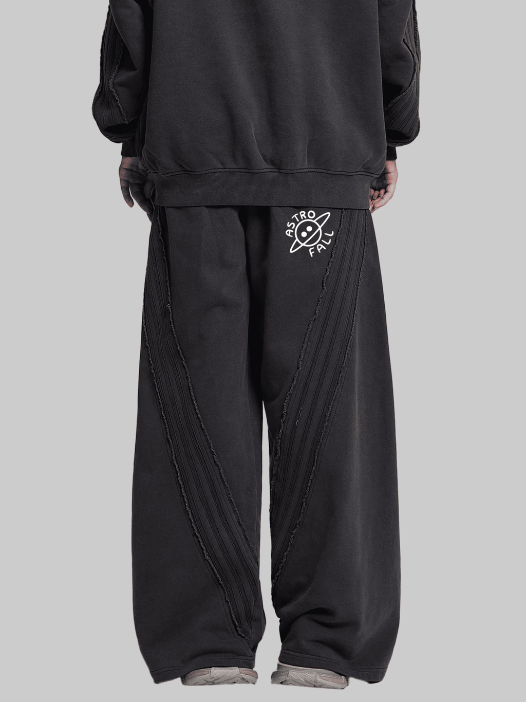 Person wearing black pants with a white logo on a gray background