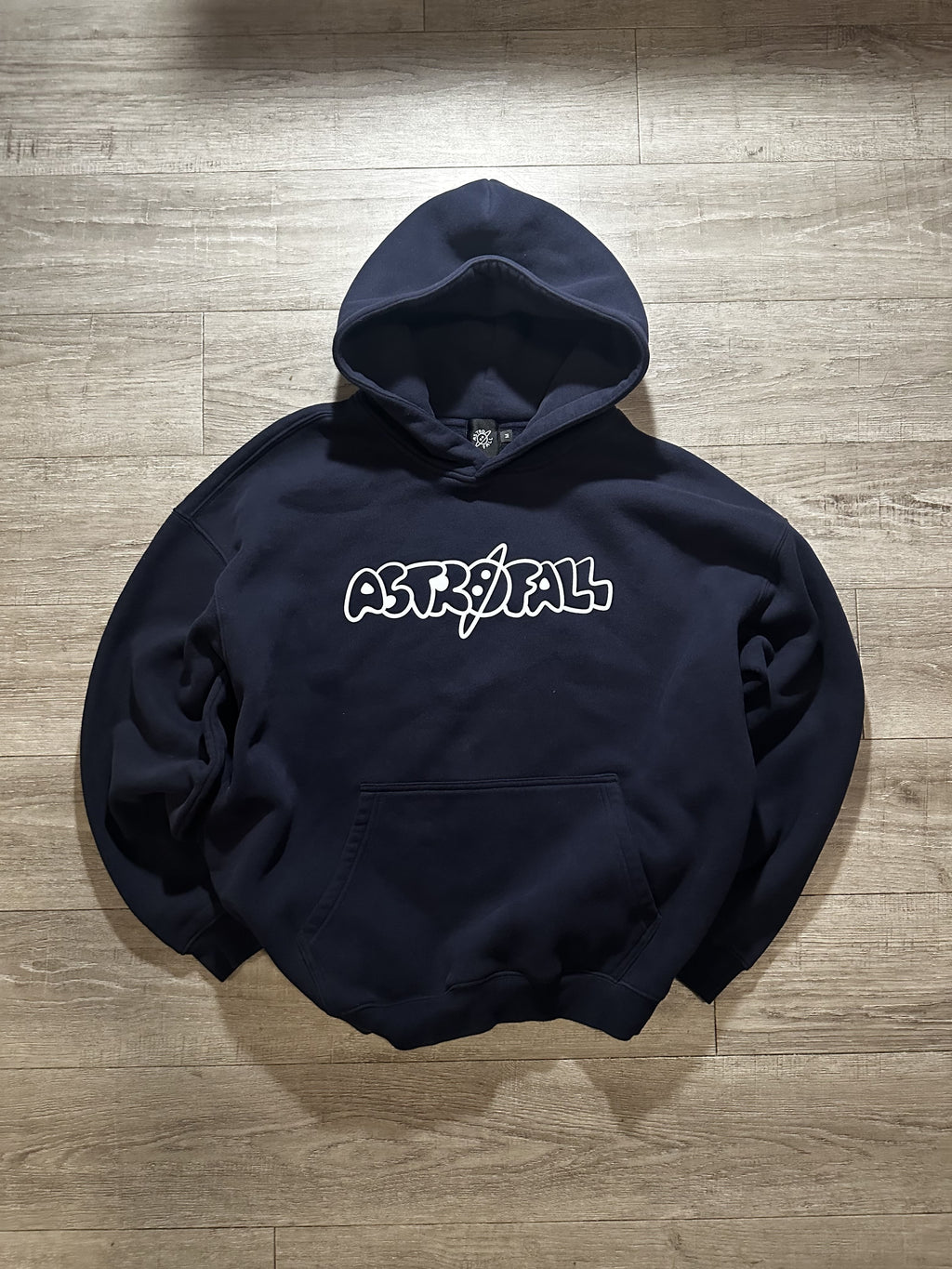 Black hoodie with 'ASTRAL' logo on a wooden floor